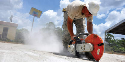 A construction worker uses a saw to cut concrete.